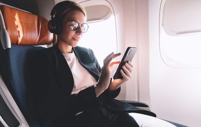 Woman in airplane holding her phone 